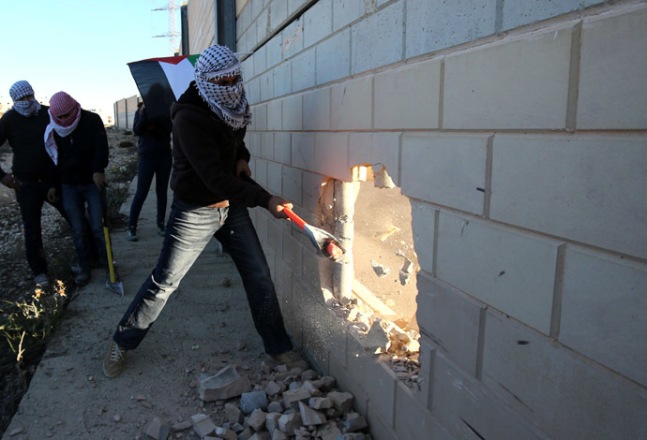 Jovens palestinos rompem partes do muro situado entre Jerusalém e Ramallah, para lembrar os 25 anos da queda do muro de Berlim. Foto: AFP Photo